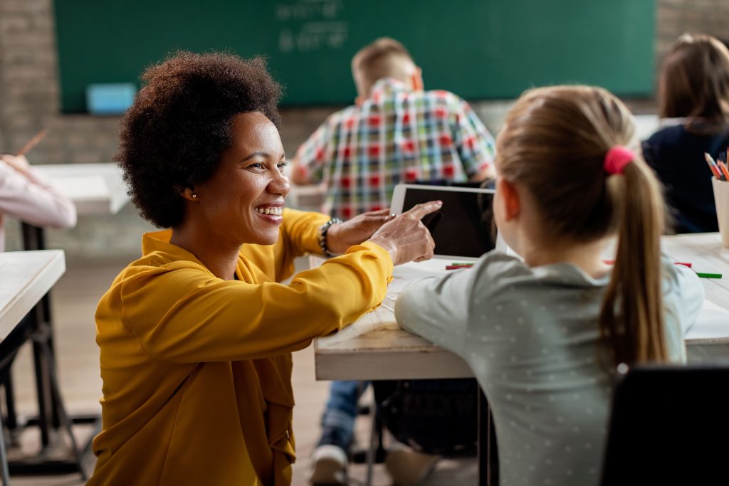 happy black teacher schoolgirl using digital tablet classroom (1)